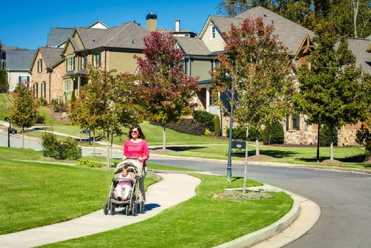 Mom strolling baby along sidewalk in Sterling on the Lake.